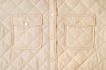 Quilted material, square quilted jacket with pocket. Beige  background texture. Close-up