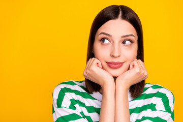 Photo of thought brunette young lady look empty space wear striped t-shirt isolated on yellow color background