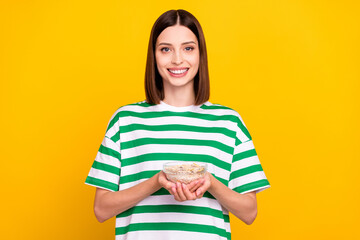 Photo of optimistic brunette young lady eat meal wear striped t-shirt isolated on yellow color background