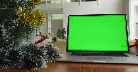 Laptop with green screen copy space on table at home, with decorated christmas tree