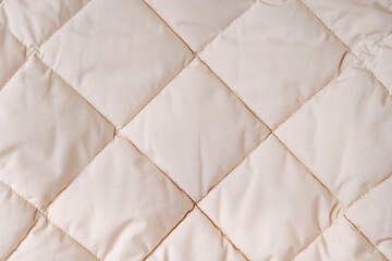 Quilted fabric background. Beige  texture blanket or puffer jacket © igishevamaria