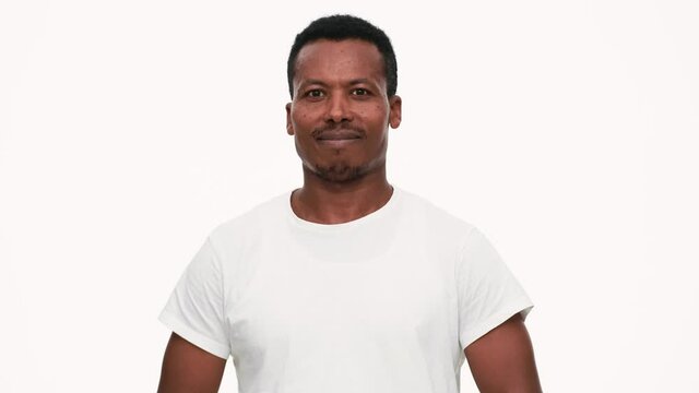 Positive African man thinking about something in white studio