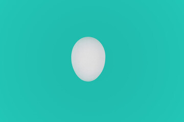 White chicken egg isolated on a turquoise background