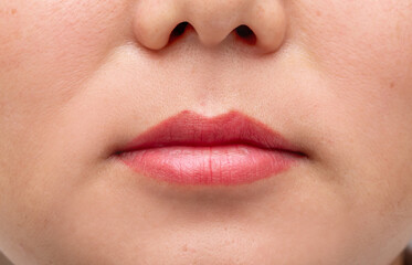 Fototapeta premium Lip augmentation. Beautician injects hyaluronic acid into the lips of a girl with a syringe. The cosmetologist doctor performs the procedure in the cosmetology office. Plastic surgery.