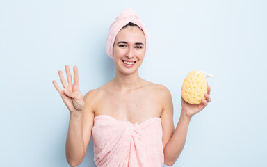 young pretty woman smiling and looking friendly, showing number four. shower and sponge concept