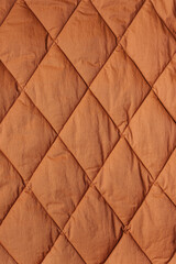 Quilted fabric background. Brown texture blanket or puffer jacket