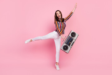 Fototapeta premium Photo of impressed funky young lady wear striped shirt dancing holding boom box smiling isolated pink color background