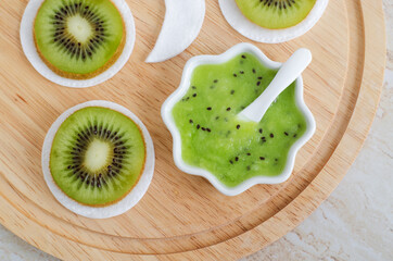 Fresh kiwi fruit puree in a small white bowl and cotton pads. Homemade face or eye mask, natural...