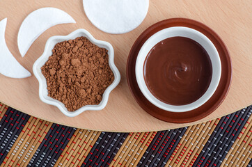 Cocoa powder and dark chocolate face and body mask in a bowl. Homemade beauty treatment and spa recipe. Top view, copy space.