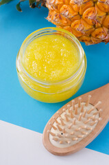 Homemade pineapple fruit scrub (bath salt, foor soak, facial mask) in a small glass jar and wooden hairbrush. Natural beauty treatment and spa recipe. Copy space