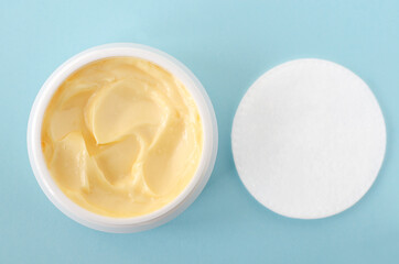 Yellow facial mask (banana face cream, shea butter hair mask, body butter) and cotton pad. Natural skin and hair concept. Light blue background. Top view, copy space.