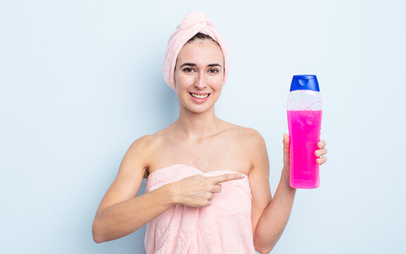 young pretty woman smiling cheerfully, feeling happy and pointing to the side. shower and shapoo concept