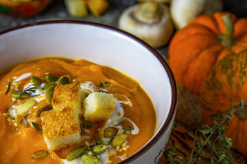 Autumn vegetarian pumpkin and carrot soup with cream, croutons and seeds. Comfort food, autumn and winter healthy slow food concept