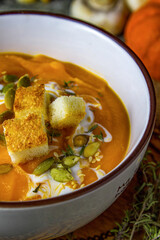 Autumn vegetarian pumpkin and carrot soup with cream, croutons and seeds. Comfort food, autumn and winter healthy slow food concept