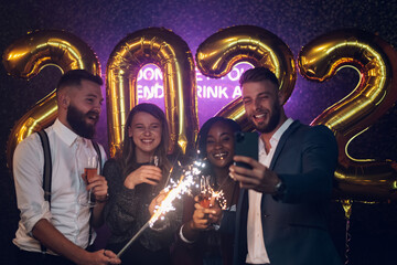 Happy group of friends celebrate New Year's Eve and taking selfie with a smartphone