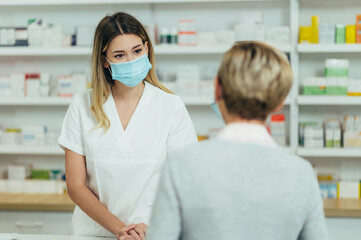 Fototapeta na wymiar Female pharmacist wearing protective mask serving a customer patient