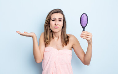 young pretty woman feeling puzzled and confused and doubting. hairbrush concept