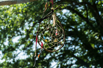 Dream Catcher with tree leaves in background -- some sunlight coming through the leaves - medium close 