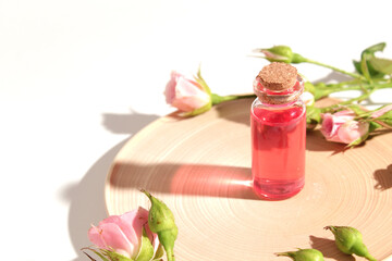 Homemade skincare natural rose water or essential oil product. Pink rose flowers and cosmetic glass bottle for moisturizing serum, facial toner, cleansing, makeup remover or treat acne.