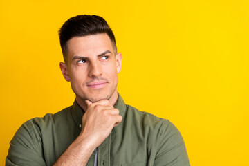 Photo of young handsome man hand touch chin think curious look empty space isolated over yellow color background