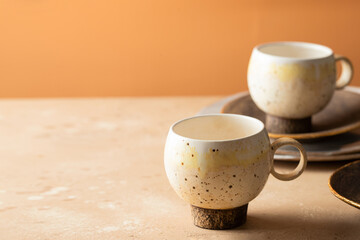 Craft ceramic collection in beige brown tone.  Handmade plates, cups  on  biege  background. copy space
