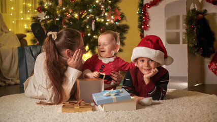 Cute baby boy playing with brother and mother on Christmas eve. Families and children celebrating winter holidays.