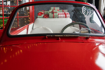 Fototapeta premium Large number of gifts are loaded into the open trunk of a red retro car