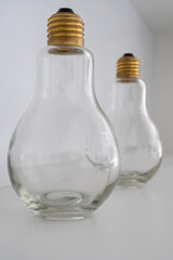 Two light bulbs with a gold socket standing one after another on a white background