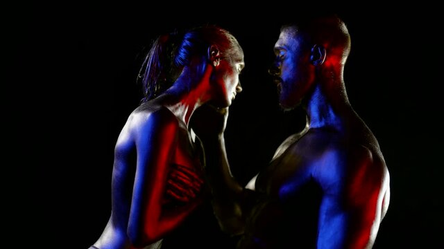 stunning figures of man and woman in darkness, skin is covered by shiny paint