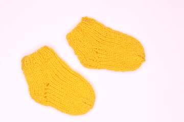 Little yellow knitted baby socks on white background 