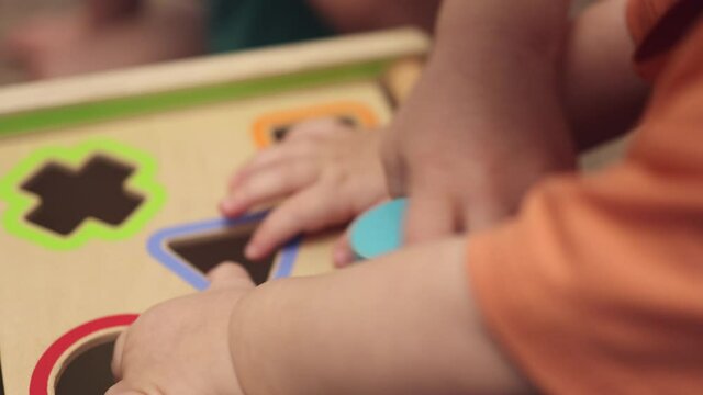 little baby kids brothers hands playing with wooden Montessori educational blocks shape sorter toy. children home learning match different color cubes to shape holes. early Infant developing concept