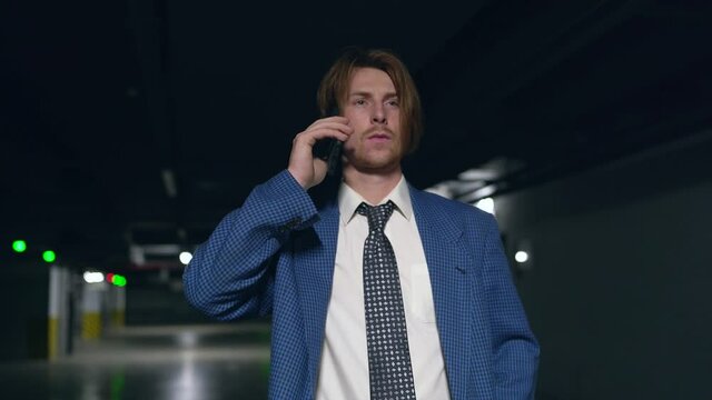 readhead business man in a blue suit talking on the phone in the parking lot
