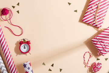 Top view of Christmas gifts, yarn, clock, and decors on a beige background