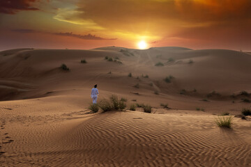 Fototapeta na wymiar Beautiful desert landscape during sunset and golden hour with very dramatic sky with a person walking between dunes