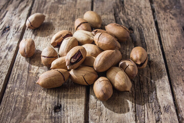 Pecan nuts on a wooden table. Heap or stack of pecan. Cracked and opened pecan nuts and nuts in shell.