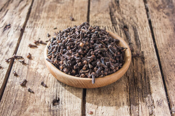 Clove seeds close-up. Dried clove seeds in a wooden bowl , Clove seasoning on the table.