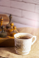 A cup of coffee and an old wooden chess set