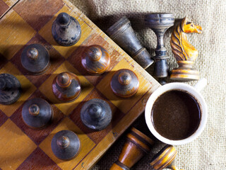 A cup of coffee and an old wooden chess set