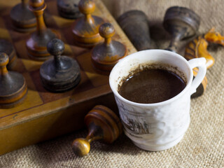 A cup of coffee and an old wooden chess set
