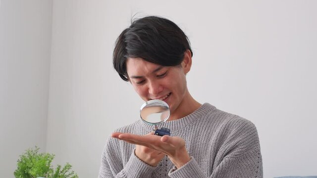 ルーペでミニカーを見る男性