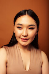 Naklejka premium young pretty asian woman cheerful smiling posing on warm brown background, lifestyle people concept