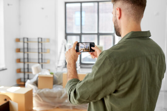 moving, people and real estate concept - man with smartphone taking picture of new home