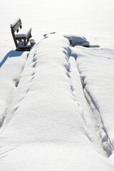 Wooden pier and bench covered with snow