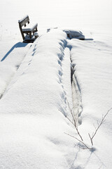 Wooden pier and bench covered with snow