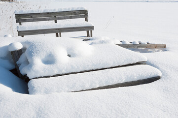 Wooden pier and bench covered with snow