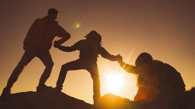 help team concept. team silhouette of climber stretching a helping hand to a friend. business teamwork success concept. silhouette business travel three tourists pull a sunlight helping hand