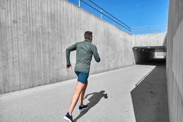 Fototapeta na wymiar fitness, sport and healthy lifestyle concept - young man running out of tunnel
