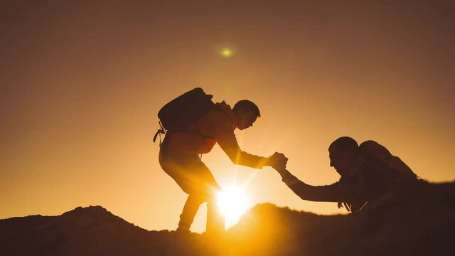 help team concept. team silhouette of two climber stretching a helping hand to a friend. business teamwork success concept. silhouette business travel sunlight tourists pull a helping hand