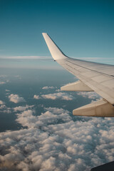 Vertical shot of the wing of the airplane over the cloudy blue sky