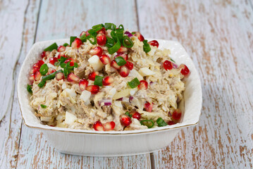 Fresh salad with meat, vegetables and pomegranate on white plate in a wooden table. close up